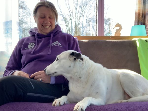 Katharine Brunsch sitting calmly beside Chloe, her white Spanish rescue dog, showing a quiet moment of trust and connection before touch.